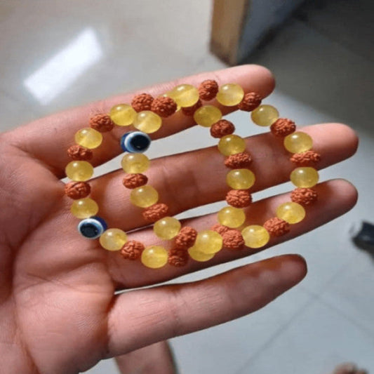 Hand holding a bracelet with yellow beads and orange and brown accents.