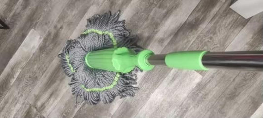 Mop with a green handle cleaning a wooden floor.