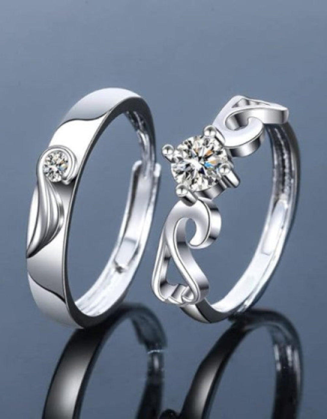 Two silver-plated adjustable finger rings with studded details, one with a simple band and the other with a more intricate design including a flower-like pattern.
