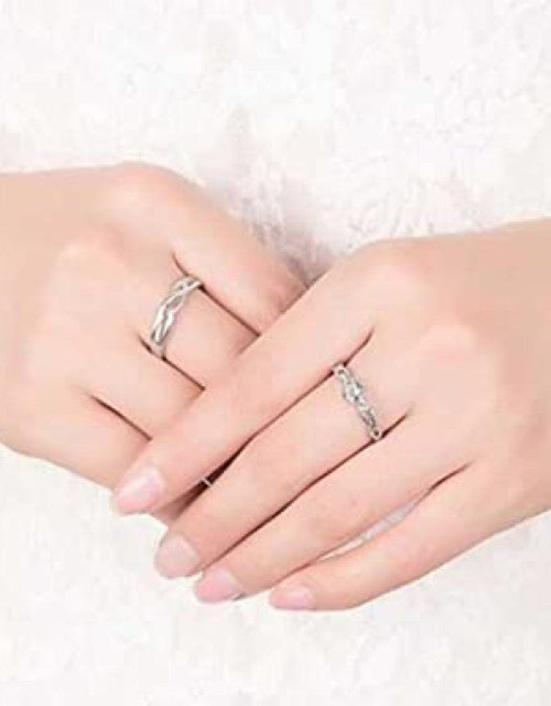 Close-up of two hands wearing silver rings on a white background