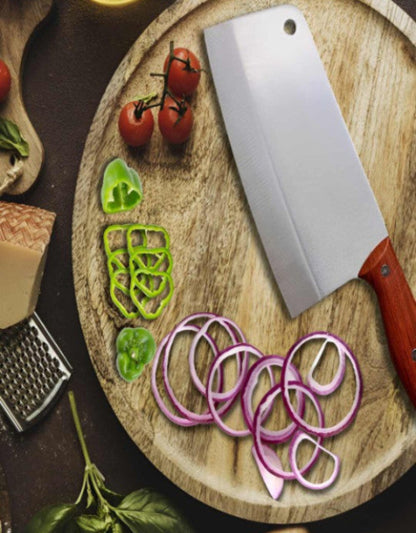 Wooden cutting board with sliced vegetables and a cleaver