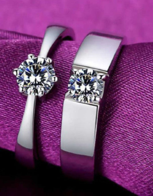 A stainless steel zircon sterling silver plated ring set with one larger solitaire diamond-like stone and two smaller stones on the band, displayed on a purple fabric.