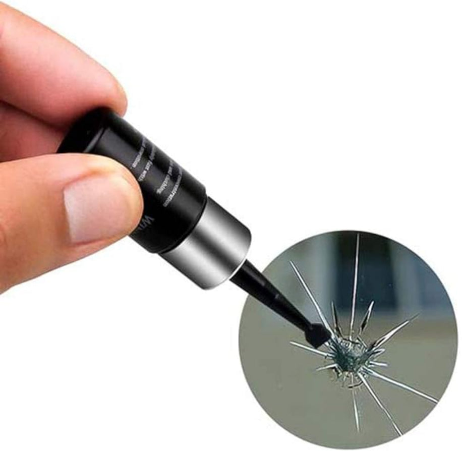 Hand holding a black and silver tool near a cracked surface